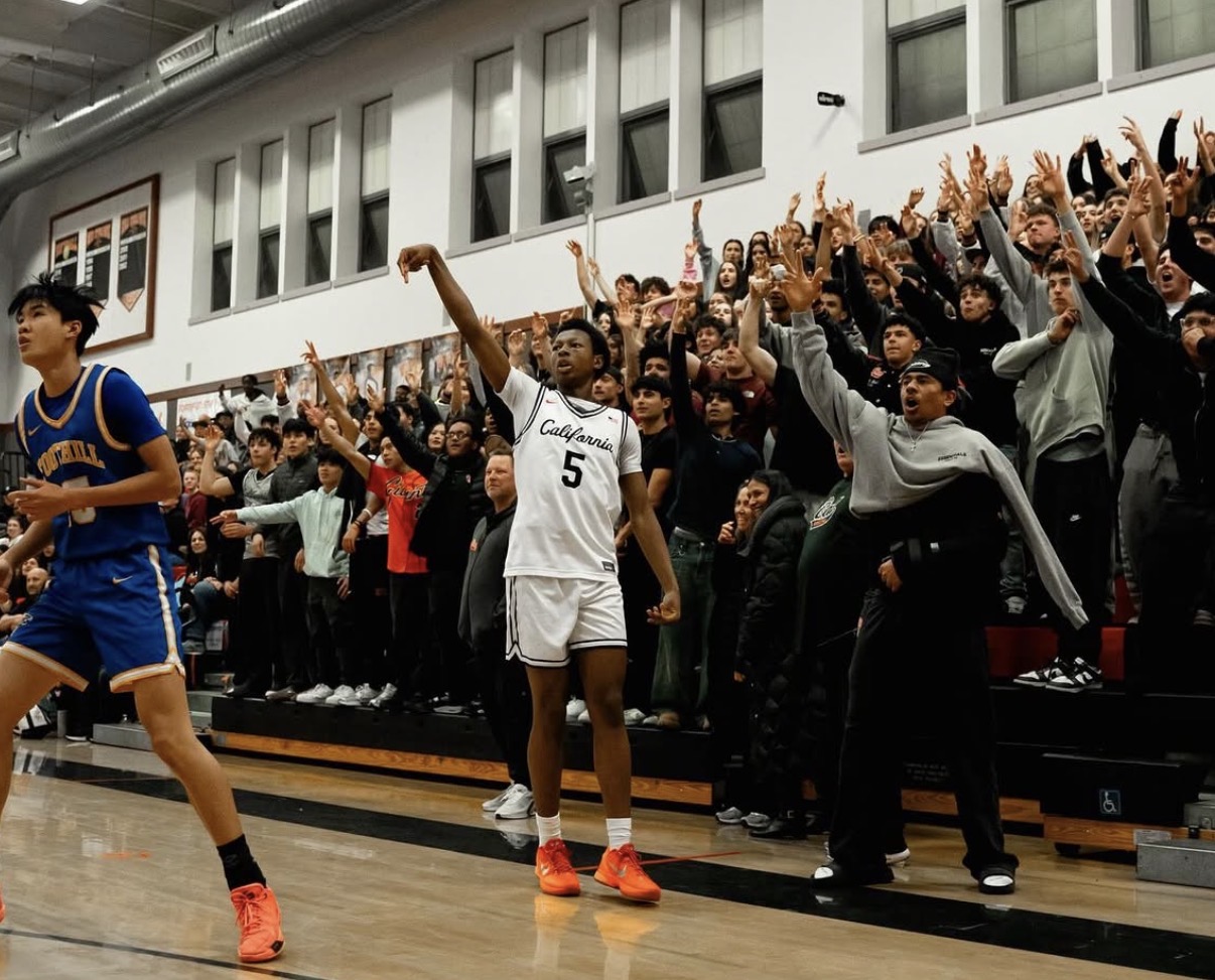 Cal High player #5 celebrating with arm raised in front of a packed roaring student section